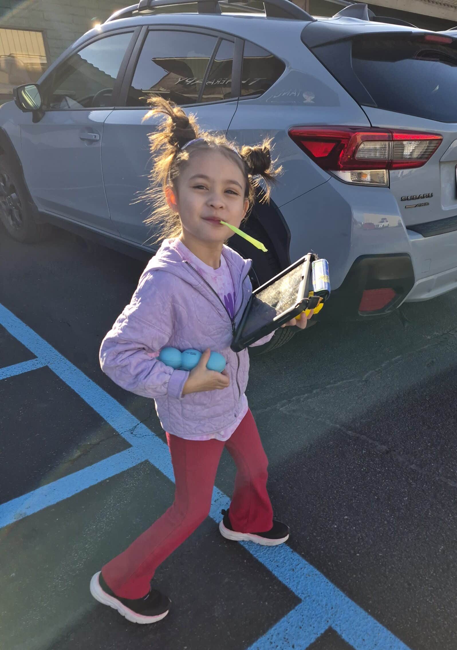 Happy girl holding a tablet and toys, embodying joy for able families.