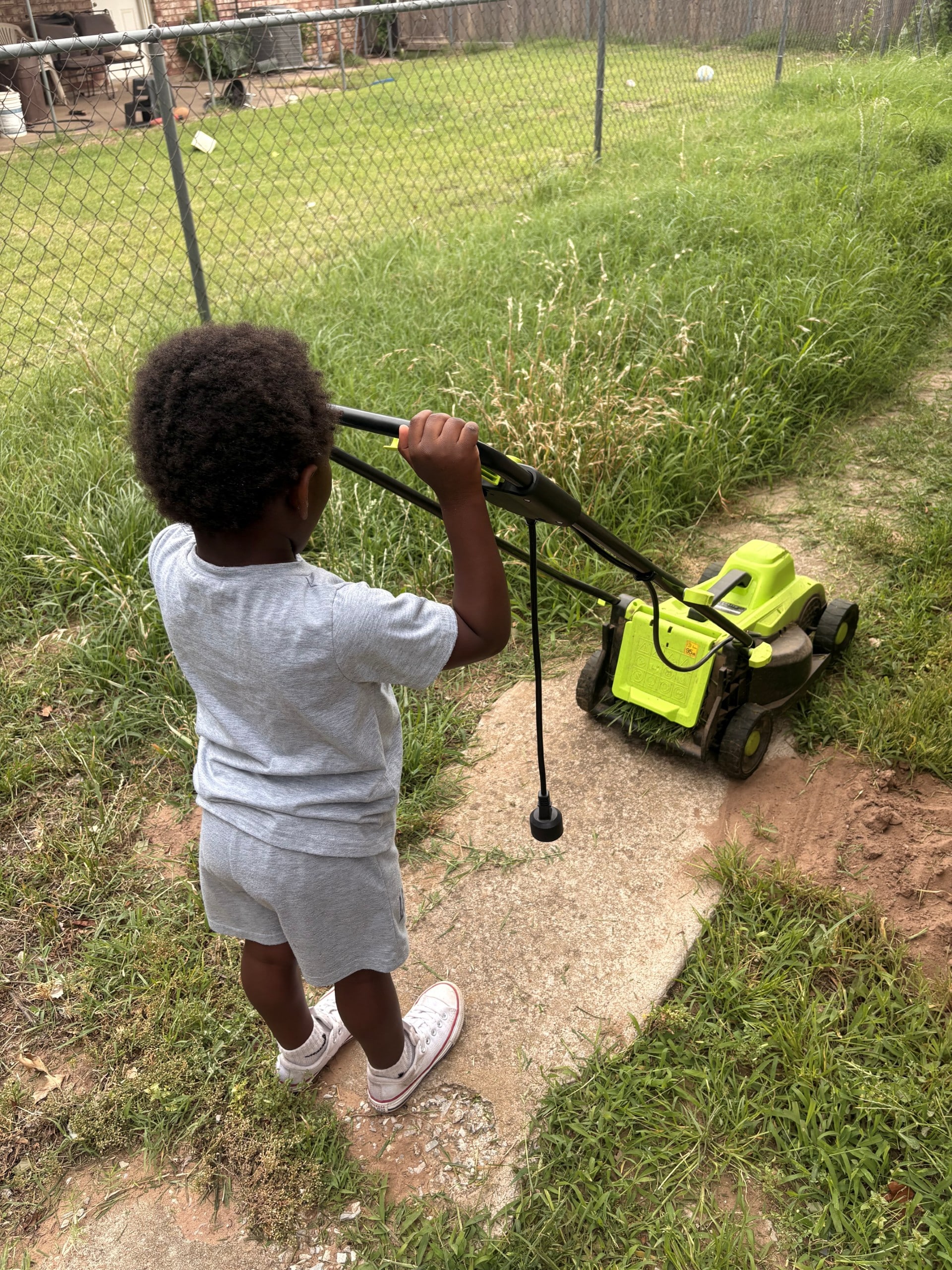 Child mowing grass in a backyard, promoting active lifestyles for able families.