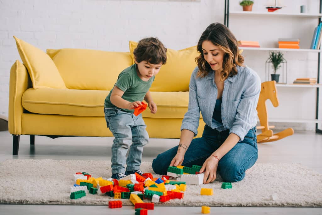 Mother and son enjoy building with colorful blocks on a cozy living room carpet.