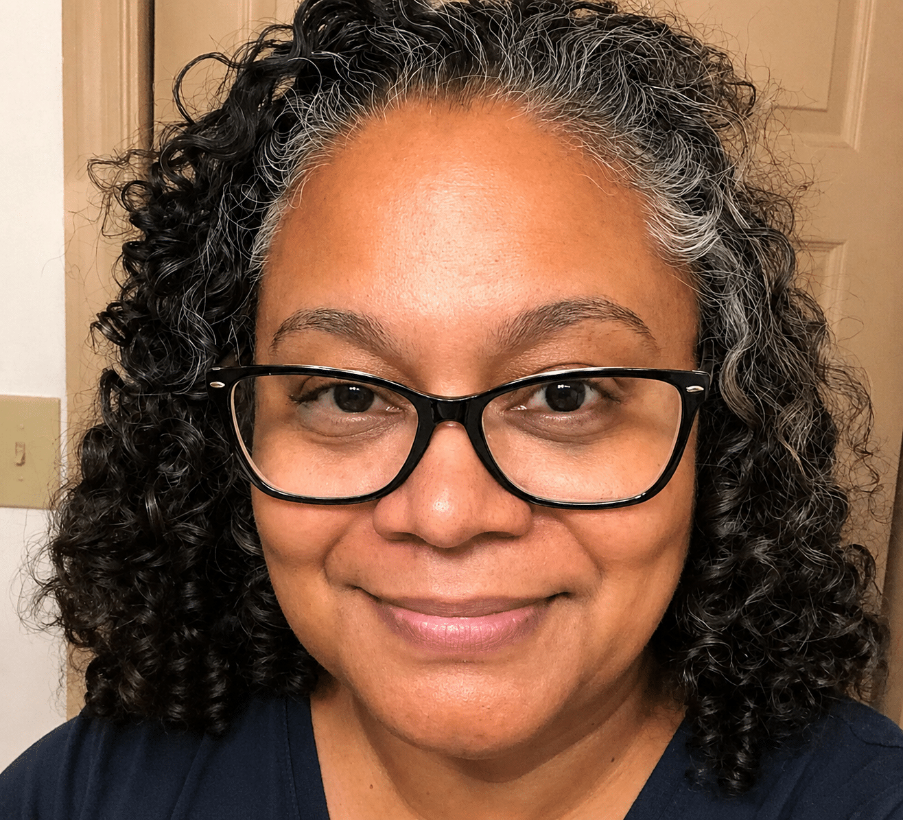 A smiling woman with curly hair and glasses, exemplifying ablefamilies spirit.