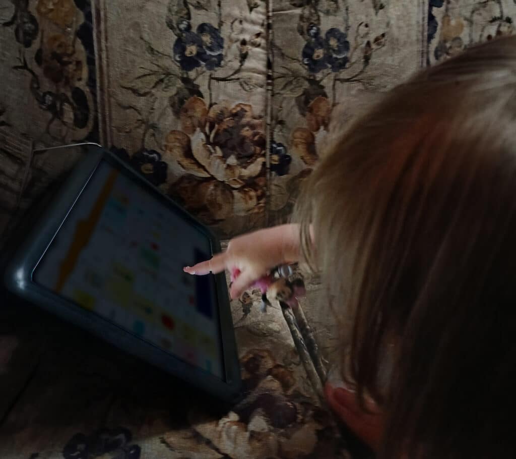 Toddler engaged with a tablet, exploring real-life apps for able families.