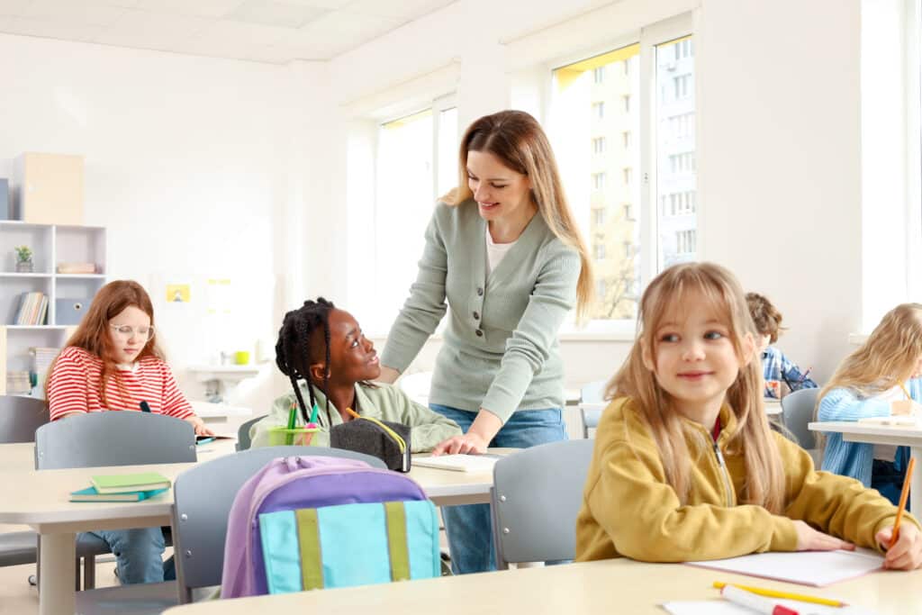 Teacher assisting students in a bright, engaging classroom learning environment.