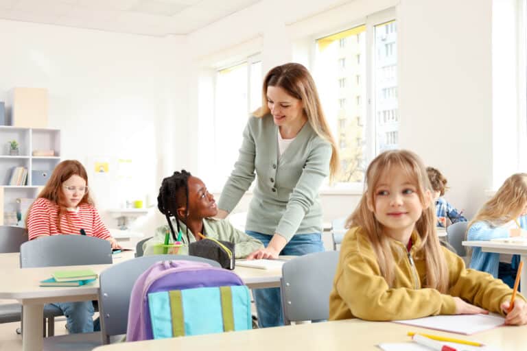 Teacher assisting students in a bright, engaging classroom learning environment.