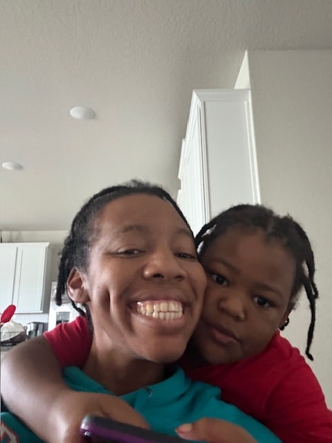 Jayden hugging his mom Jasmine from behind as they smile for the camera