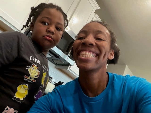 Jasmine smiling in a selfie in the kitchen with her son Jayden beside her