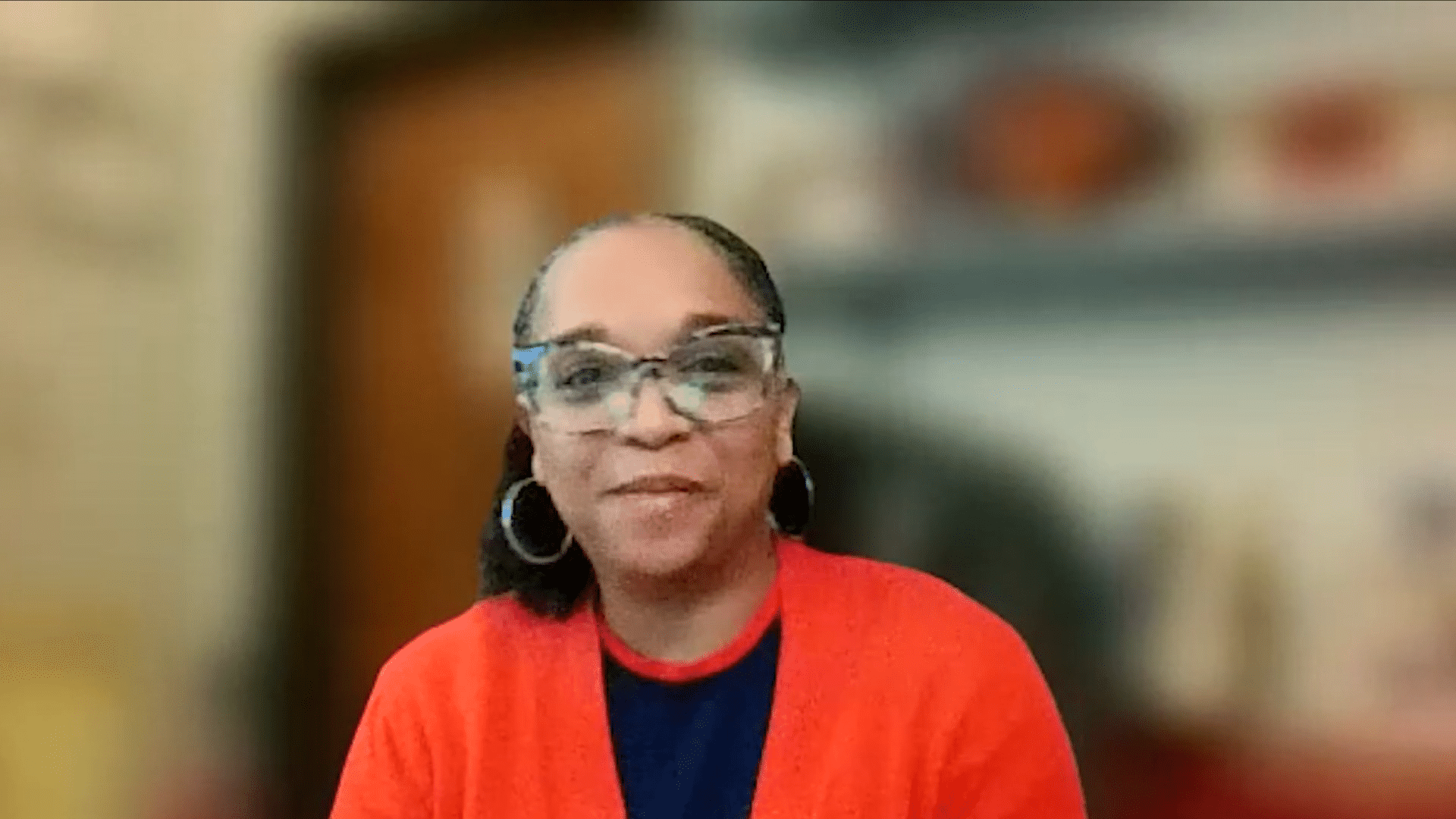 Smiling person in orange cardigan shares inspiring success stories for motivation.