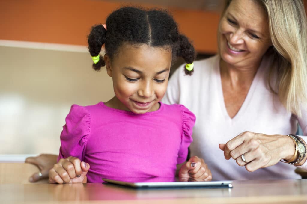 A girl and a woman enjoying a fun learning moment with a tablet together.