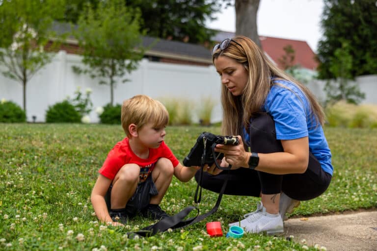 Child learns to use the Quicktalker Freestyle AAC device skills with at home with a parent in a vibrant outdoor setting.