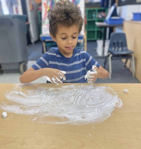 Child exploring creativity while playing with foam in a classroom setting.
