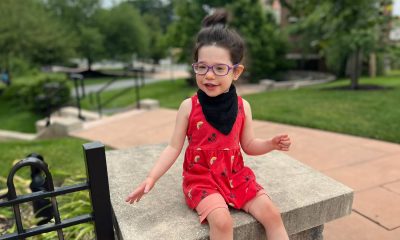 Smiling child in a red dress enjoys playing outside in a park.