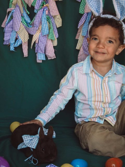 Happy child with a bunny, celebrating Easter with colorful eggs and decorations.