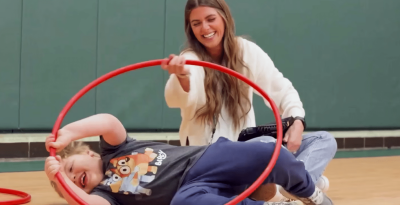 A woman and child joyfully play with hula hoops indoors, promoting fun and fitness.