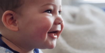 Happy baby smiling brightly, showcasing joy and innocence in a warm, cozy setting.