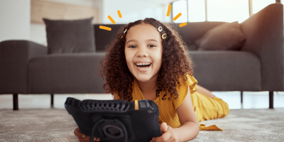 A joyful girl playing with a tablet on the floor in a cozy living room.