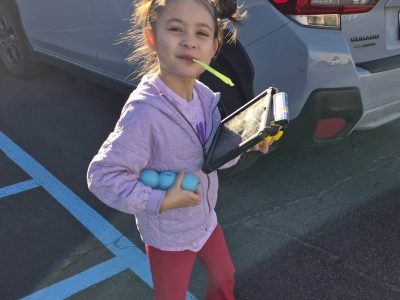 Happy girl holding a tablet and toys, embodying joy for able families.