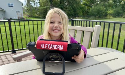 Happy child enjoying tablet playtime outdoors in a green backyard setting.