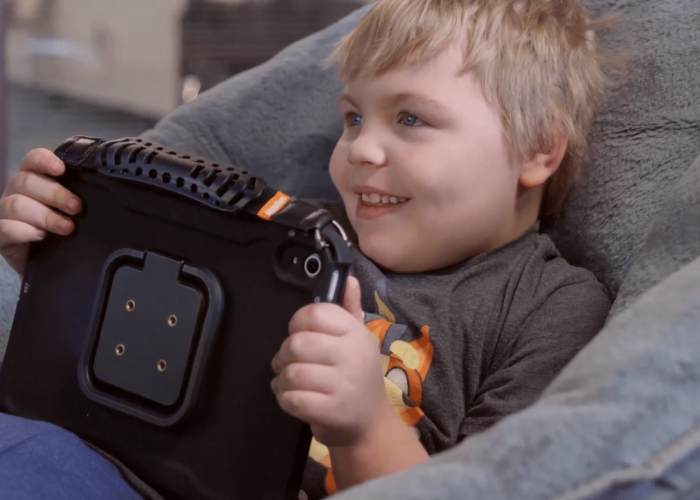 Happy child enjoying a tablet while relaxing in a cozy chair.