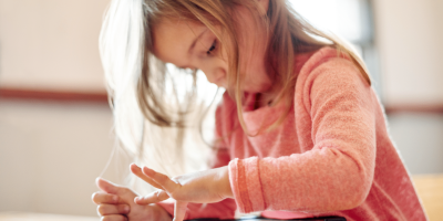 Child engaged with tablet, learning and exploring technology in a cozy environment.
