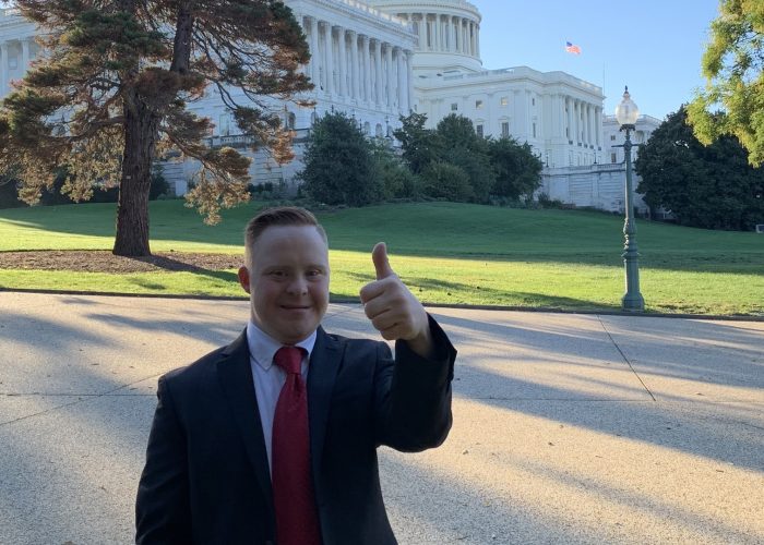 Young man gives a thumbs up in front of the U.S. Capitol building.