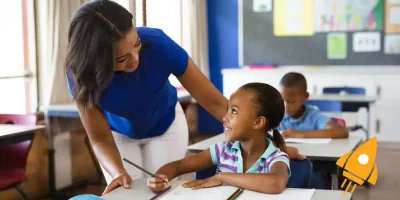 Teacher engaging with students in a classroom, promoting positive learning interactions.