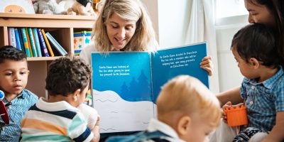 Teacher shares a Christmas story with engaged children in a cozy classroom setting.