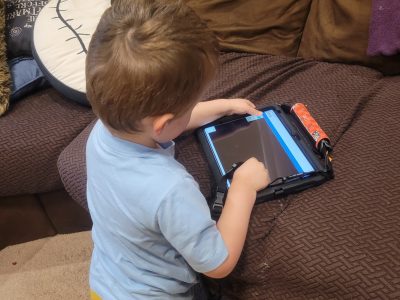 Toddler engaging with a tablet for learning and educational play on a couch.